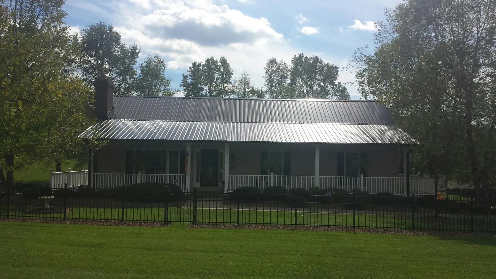 Gray metal roof on a brick ranch with a full width front porch — Gutter Guard Installation work by our crew in Mooreland