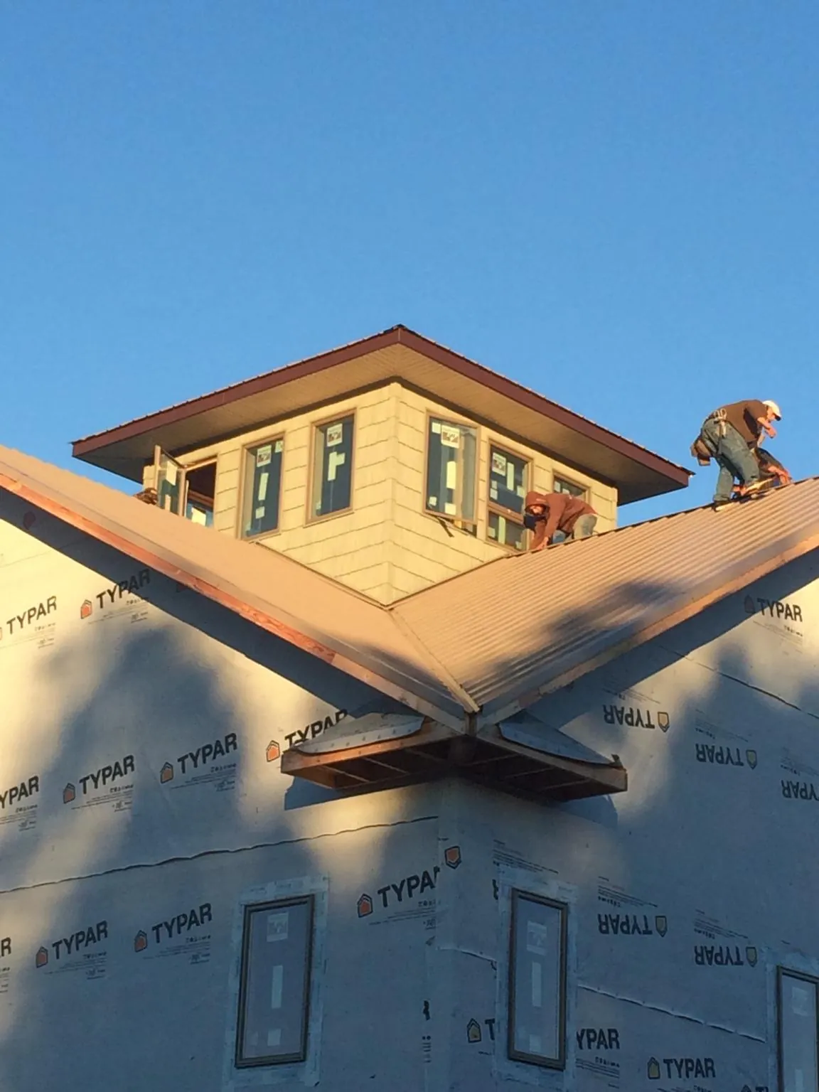 Roofers working around a rooftop cupola on a new metal roof at sunset — Roof Waterproofing in Mooreland by Roofing Brothers